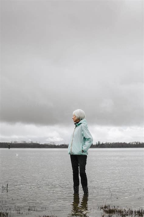 Active Senior Woman Outside Exploring Wetlands On Cloudy Day By Stocksy Contributor Rob And