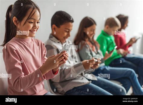 Diverse Children Using Phones Playing Mobile Games Over Gray Background