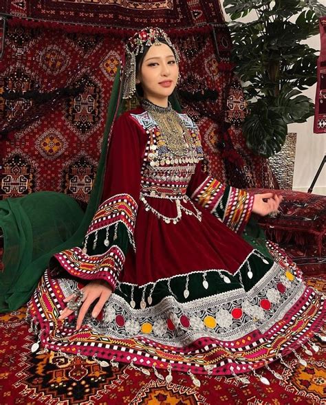 A Woman Sitting On Top Of A Rug Wearing A Red And Green Dress With An