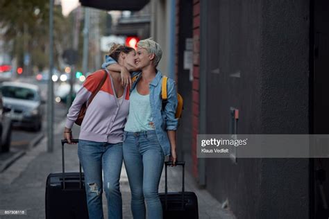 Lesbian Couple Walking Together With Rolling Suitcases Photo Getty Images