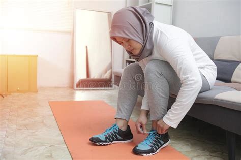 Young Asian Muslim Woman Tying Her Shoelaces In Her Bedroom Preparing