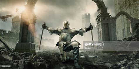 Medieval Knight Kneeling With Sword In Front Of Building Ruin High Res
