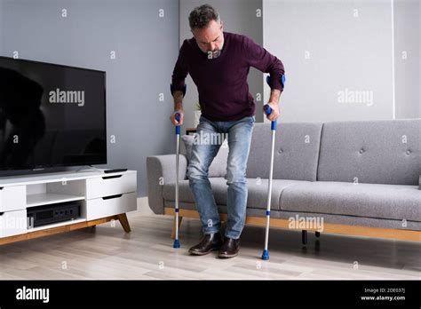 Elderly Man Using Crutches To Walk On Carpet Stock Photo Alamy