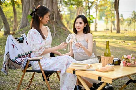 Two Beautiful Asian Women Picnic In The Park Sipping White Wine