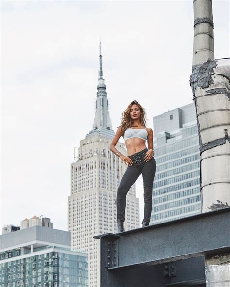 A Woman Standing On Top Of A Metal Structure In Front Of A Cityscape