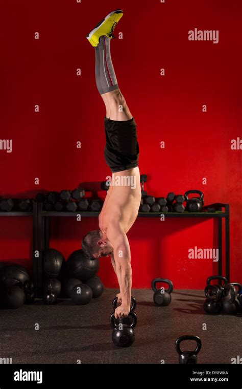 Kettlebell Handstand Man Workout In Red Gym With Dumbbells Background