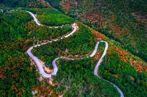 Aerial View Over Mountain Road With Many Curves Going Through Forest