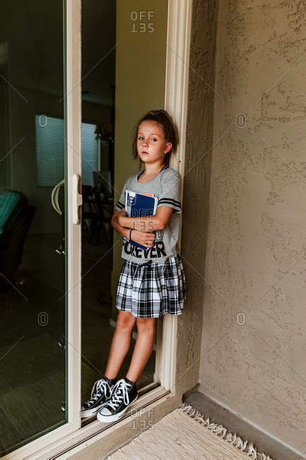 Girl Standing In Doorway Holding School Books Stock Photo