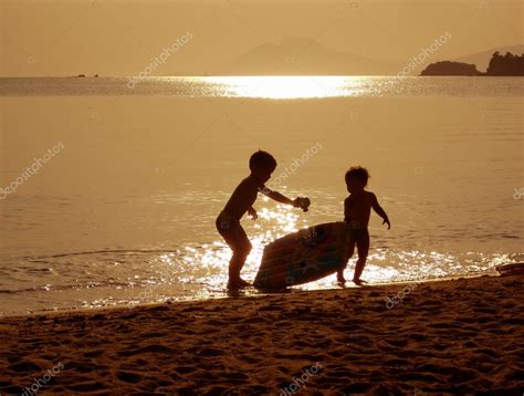 Niños Jugando En La Playa Al Atardecer — Fotos De Stock © Artida 1802274