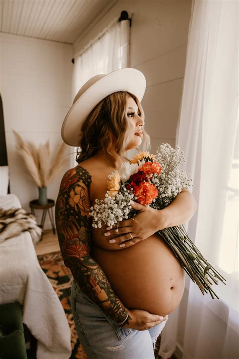 A Pregnant Woman Wearing A White Hat And Holding Flowers For Her Boho