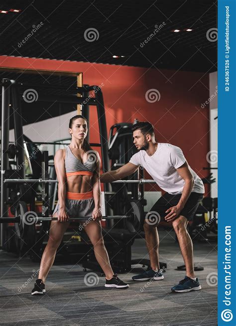 Handsome Trainer Supporting Attractive Sportswoman Lifting Stock Photo
