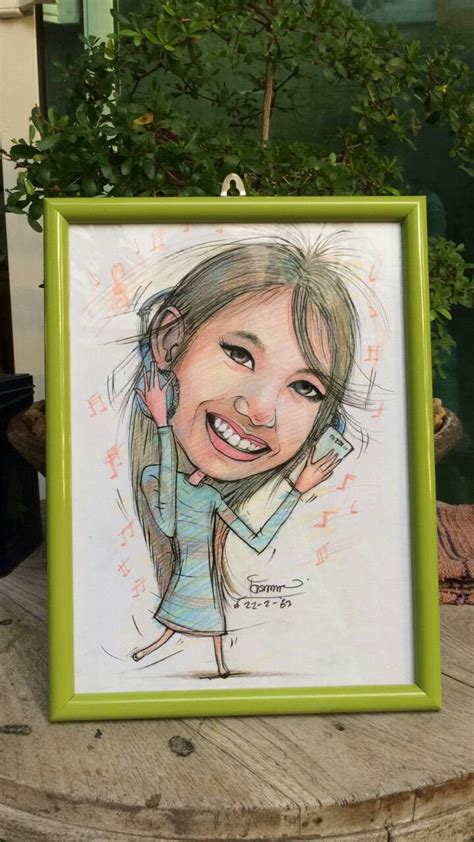 A Drawing Of A Smiling Girl In A Green Frame On Top Of A Wooden Table