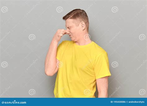 Portrait Of Mature Man Pinching His Nose And Grimacing From Disgust