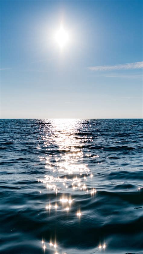 Download Wallpaper Sun On Blue Sky Is Reflected On Water 1440x2560