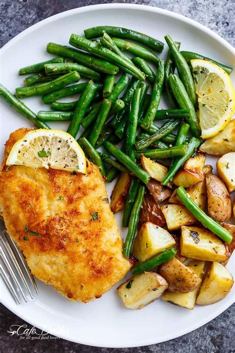 A White Plate Topped With Chicken Potatoes And Green Beans Next To A