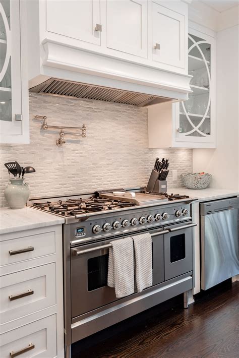 A Stove Top Oven Sitting Inside Of A Kitchen Next To White Cupboards