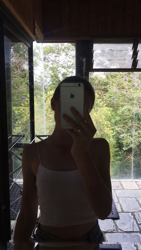 A Woman Taking A Selfie In Front Of A Window With Her Cell Phone Up To
