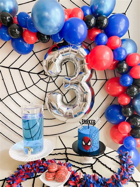 A Spiderman Birthday Party With Balloons Streamers And Cake On A Table