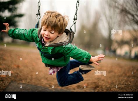 Happy Young Boy Playing On A Chain Swing At A Park Stock Photo Alamy