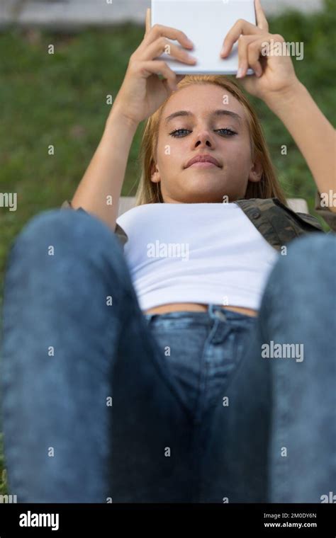 gaze of an androgynous girl in a glimpse of visibility between her raised tablet and her