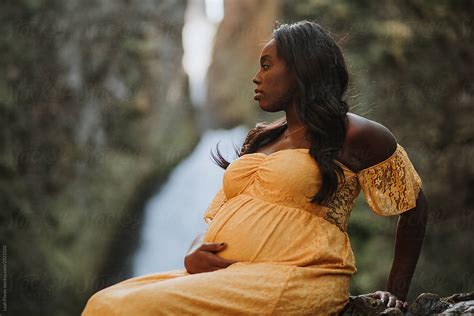 Beautiful Pregnant Black Woman Sitting In Front Of Waterfall By