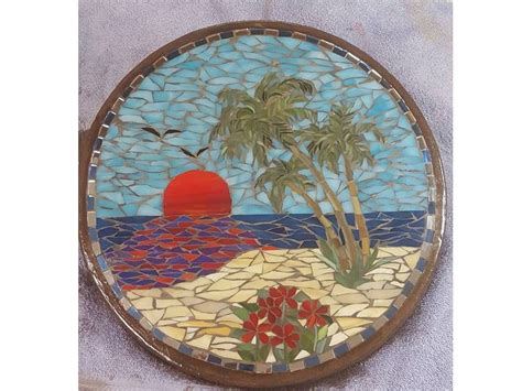 A Round Stained Glass Plate With Palm Trees On The Beach