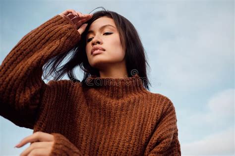 Portrait Of Gorgeous Asian Brunette Girl In Cozy Knitted Sweater Sensually Posing Outdoor Stock