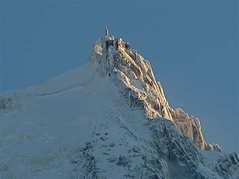 The Top Of A Snow Covered Mountain With A Sky Background