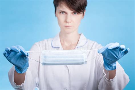 doctor in white medical coat and blue gloves shows a medical mask concept of protection from