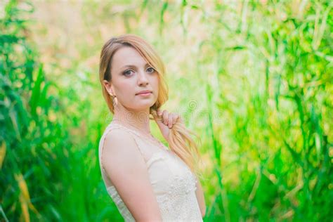 Beautiful Blonde Girl In A White Dress In The Forest Stock Photo