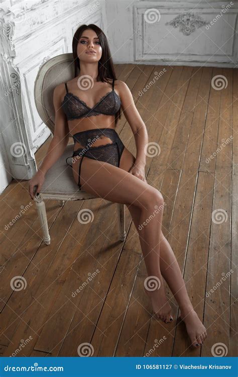Very Brunette Lady Posing In Black Lingerie Sitting On Chair Stock