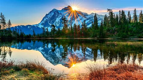 Landscape View Of White Covered Mountains Green Trees In Sunrise