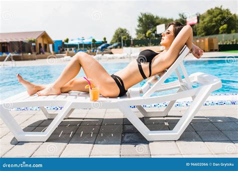 Attractive Young Women In Bikini Lying On The Deck Chair Near The Pool
