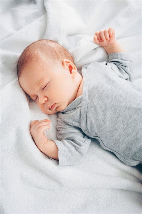 Sleeping Baby Boy In White Bodysuit In Bed With Copyspace Stock Photo