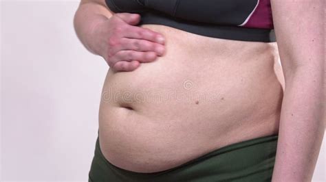 A Middle Aged Woman With Saggy Skin Defines Her Large Belly With A Measuring Tape With Turns On