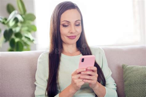 Photo Of Busy Adorable Mature Lady Wear Teal Pullover Smiling Sitting Couch Typing Modern Gadget
