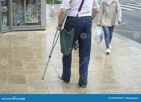 A Man With A Crutch In Town A Disabled Man Walks Down The Street Stock