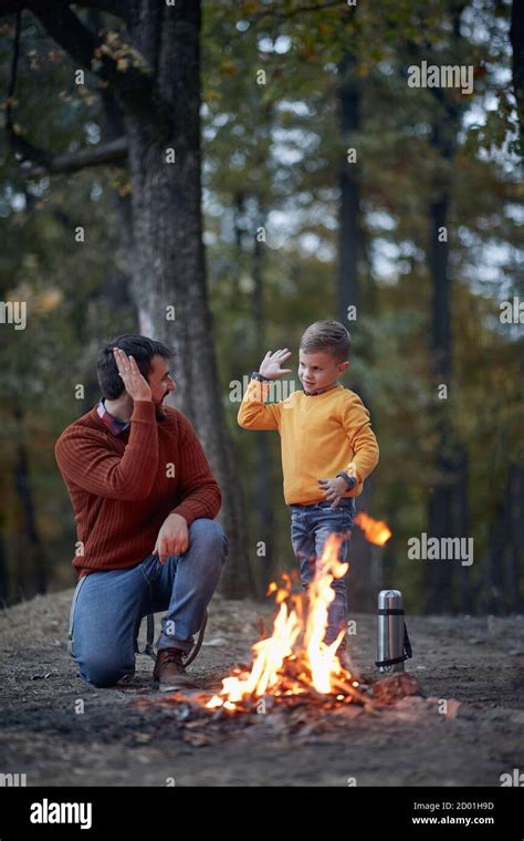 Father And Son Starting A Fire Together On A Camping Spring Or Autumn