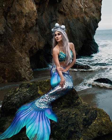 A Beautiful Mermaid Sitting On Top Of A Rock Next To The Ocean