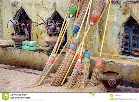 Detail Of Colorful Rustic Brooms Against Weathered Wall Stock Photo