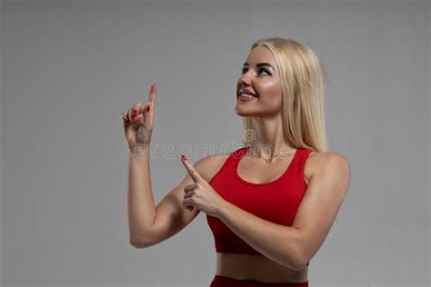 Blonde Woman In A Red Top Points Her Fingers Up To The Left Stock Image