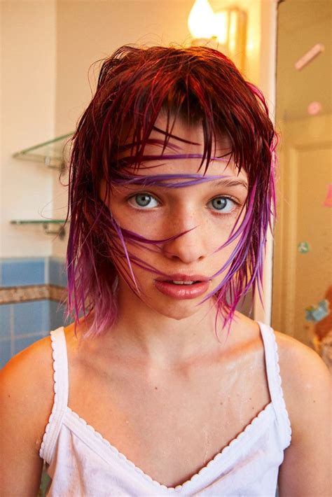 A Woman With Pink And Purple Hair Is Looking At The Camera While She