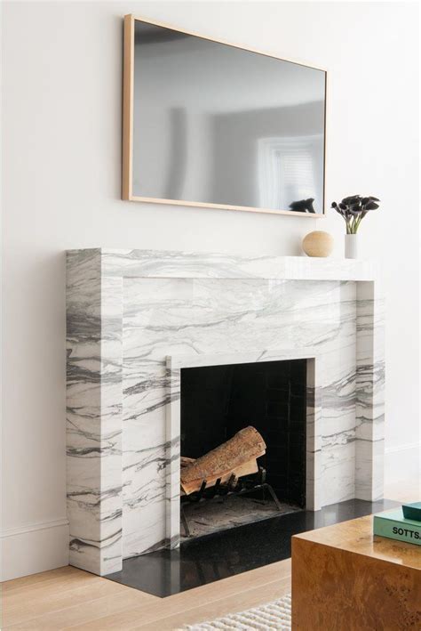 A White Marble Fireplace With A Mirror Above It