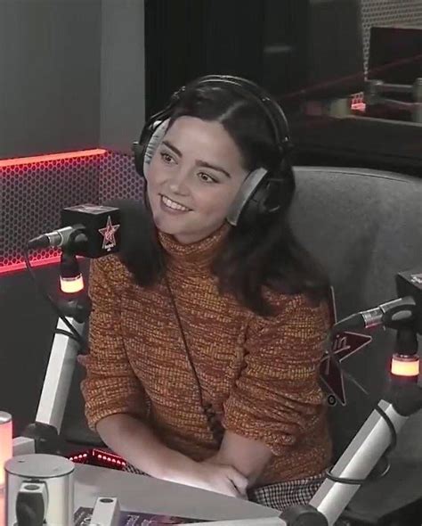 A Woman Wearing Headphones Sitting In Front Of A Microphone