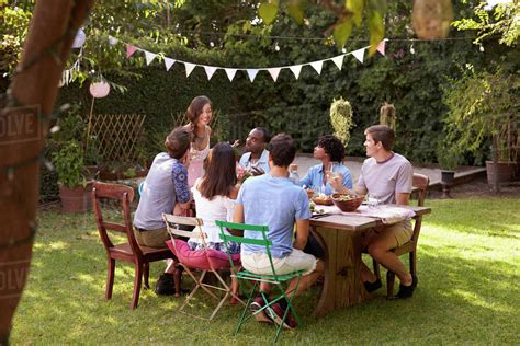 Woman Serving Food To Friends At Outdoor Backyard Party Stock Photo