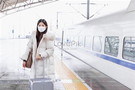 A Woman Wearing A Mask Is Standing Next To The Train Picture And Hd