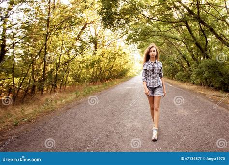 Beautiful Girl Walking On Empty Road Between Green Trees Stock Image