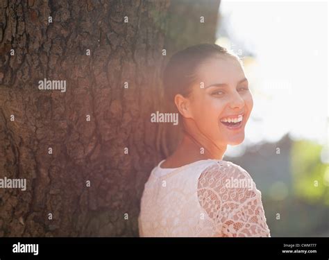Laughing Young Woman Lean Against Tree Stock Photo Alamy