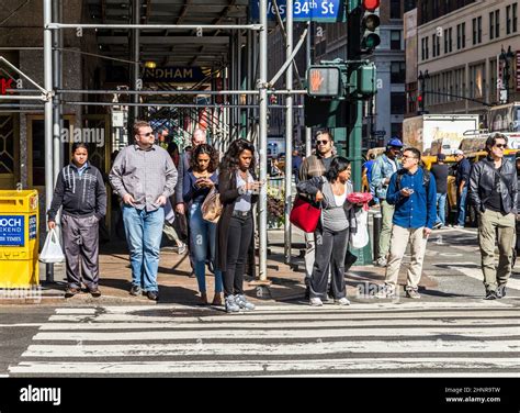 People Near Wall Street In Manhattan Cross The Street At White Traffic
