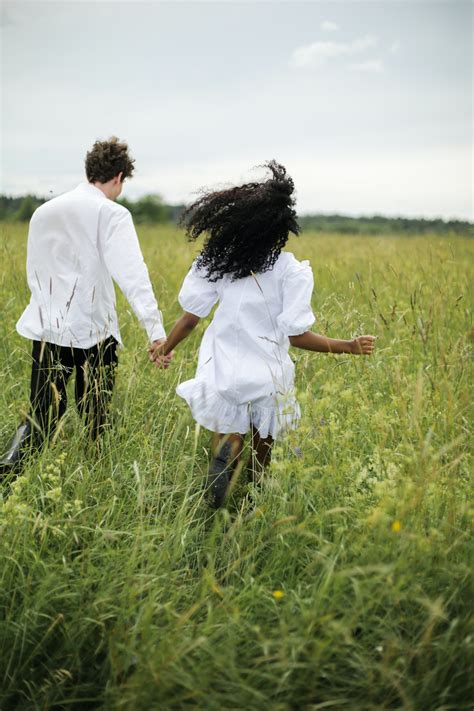 Man and Woman Holding Hands While Walking on Green Grass ...